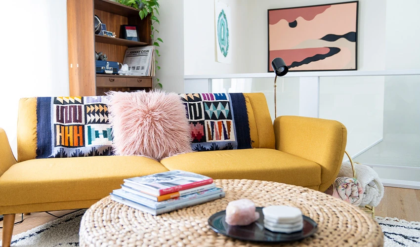 modern living room with yellow sofa and wicker ottoman