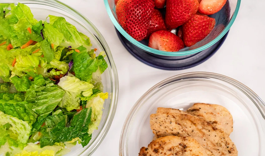 lettuce, strawberries and chicken in bowls