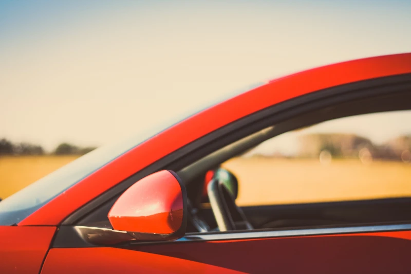 view of red car driver side window and mirror