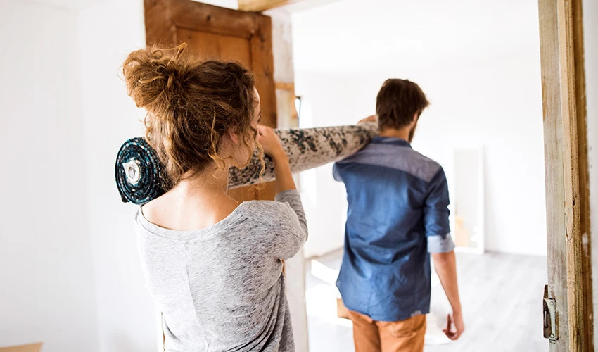 man and woman carrying roll of carpet on shoulders