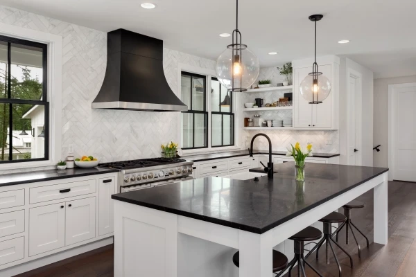 Beautiful kitchen in new luxury home. Features black countertops and island, with white woodwork and cabinetry
