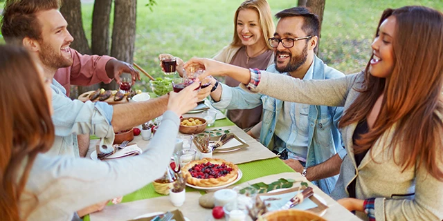 five friends toasting with glasses while dining outside