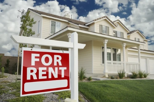 Red, right facing for rent real estate sign in front of beautiful house