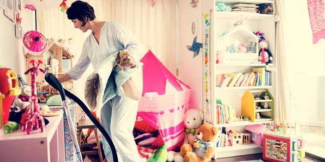 woman cleaning kids room filled with toys