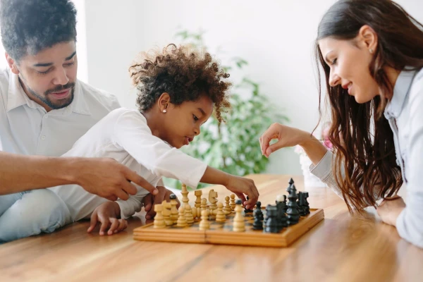 Family with a young child playing chess together