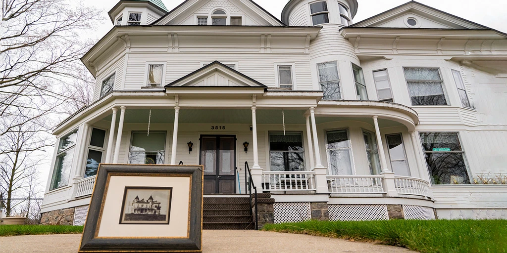 Historic home with old picture of the house sitting in front of it