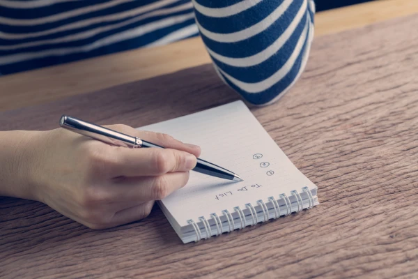 woman writing a to do list on a notebook