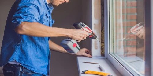 man with a drill working on a window