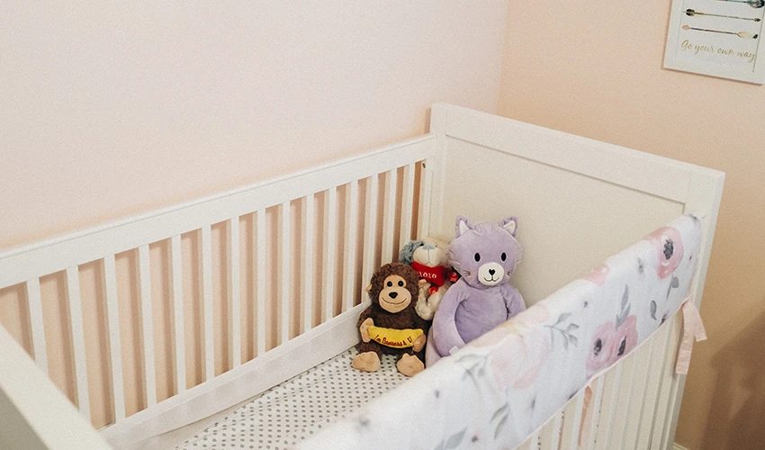 white crib with stuffed animals inside