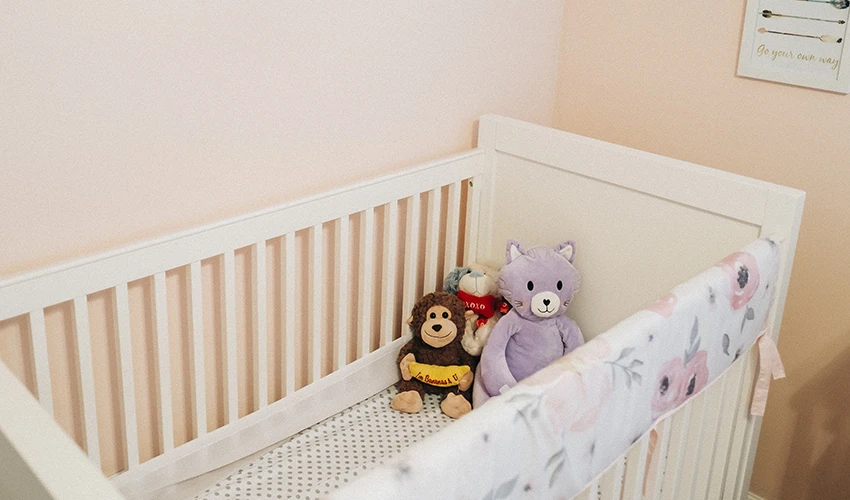 White crib with stuffed animals inside.