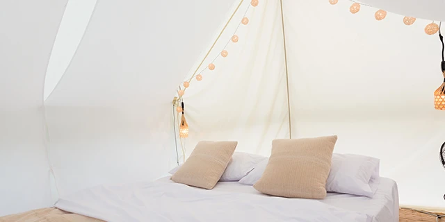 comfortable glamping tent with white bedding