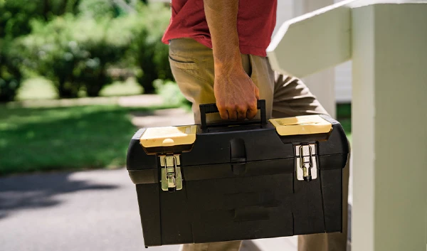 Man carrying toolbox into house