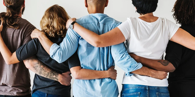 group of people facing away from each other with arms around backs