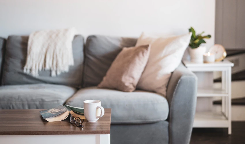 comfortable gray sofa with pillows and coffee mug on table.