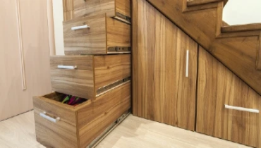 Custom built pullout cabinets on glides in slots under wooden stairs.