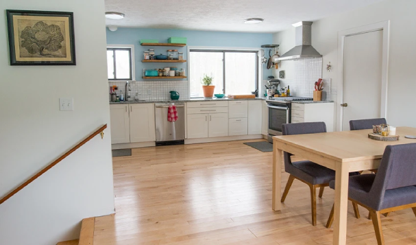 White modern eat-in kitchen with stairs leading down.