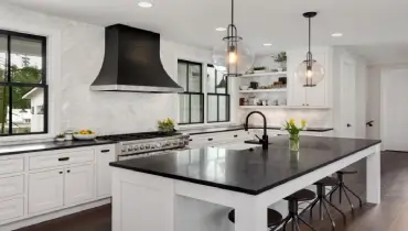 Beautiful kitchen in new luxury home. Features black countertops and island, with white woodwork and cabinetry 