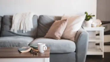 comfortable gray sofa with pillows and coffee mug on table.
