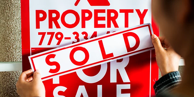 Red and white property sold sign.