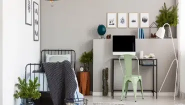 Bright grey bedroom interior with workspace that has a desk and computer