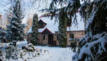Old brick house and trees in a snowy landscape.