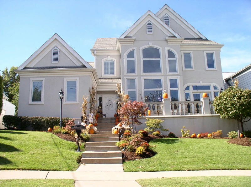 Front of two story light gray home with decorative landscaping.