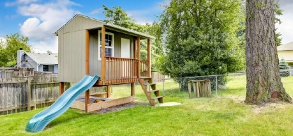 Playhouse with slide in the backyard of a residential home.