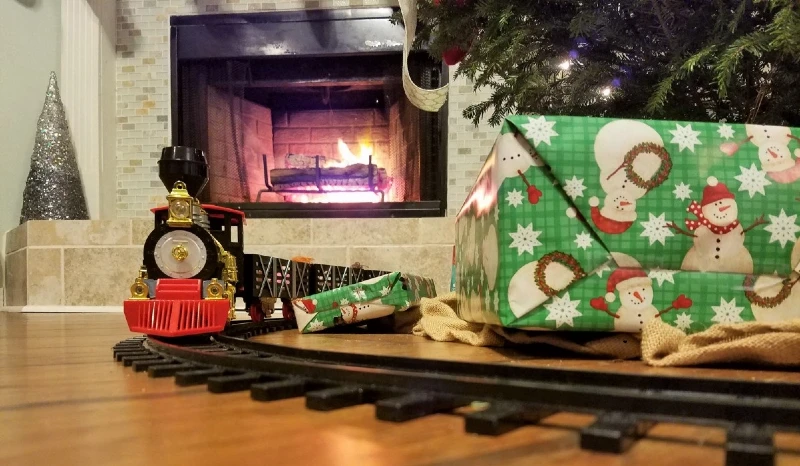 Christmas presents and train on floor under tree.