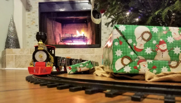 Christmas presents and train on floor under tree.