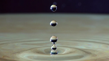 Droplets of water falling into puddle.