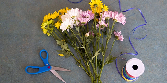 bouquet of flowers on table with scissors and blue string.