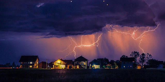 Lightning clouds storm over a group of homes.