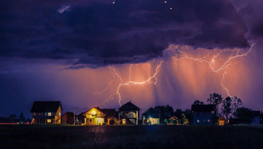 Lightning clouds storm over a group of homes.