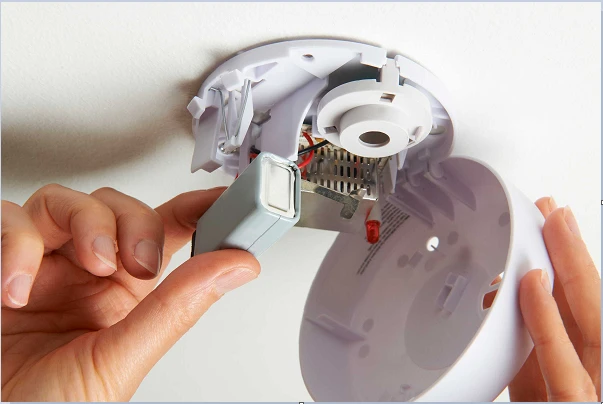 Installing battery into smoke alarm.