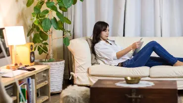 Woman sitting on the couch purchasing an item on her tablet