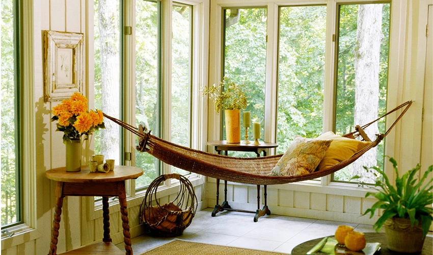Hammock in a corner with windows looking out into greenery