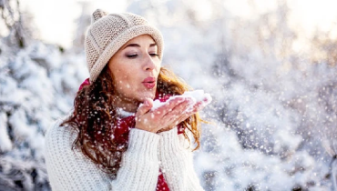 Woman blowing snow from her palms.