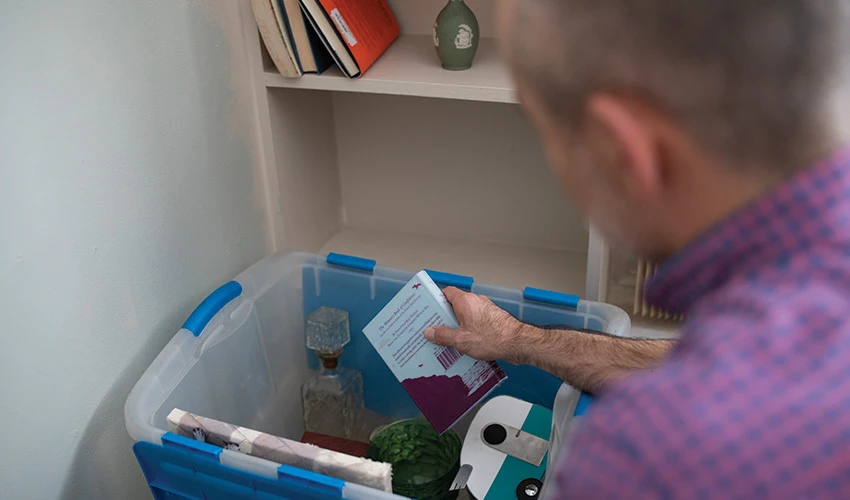 Man packing household items in a tote.
