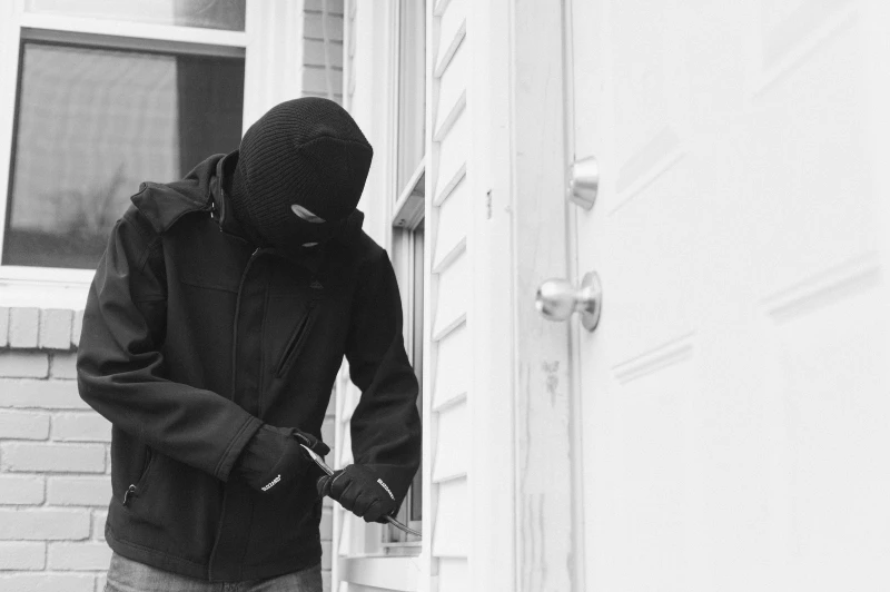 Burglar trying to pick a lock to break into a home.